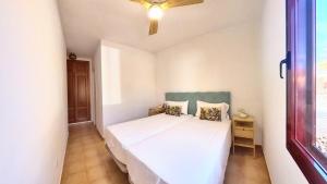 ein weißes Bett in einem Zimmer mit Fenster in der Unterkunft La Maison de Montse - Piscine Privée in Corralejo