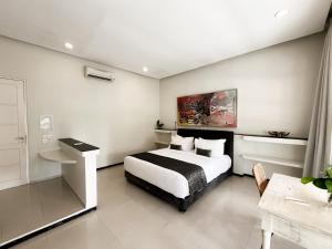 a bedroom with a bed and a desk in a room at Casa Artista By Kresna Hospitality in Seminyak