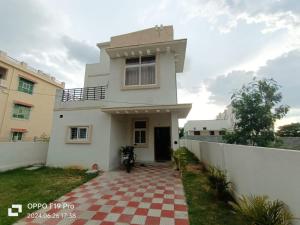 Una casa blanca con una entrada a cuadros rojos y blancos en Luxury Villa Rooms Phamacity Genome Valley, en Turkapally