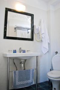 a bathroom with a sink and a mirror and a toilet at Alonia Studios & Maisonettes in Tolo