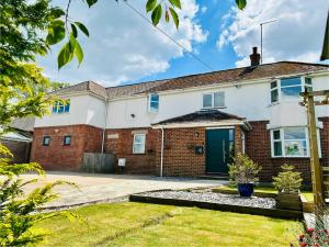 Lynwood House, Bratton في Bratton: منزل من الطوب مع باب أزرق