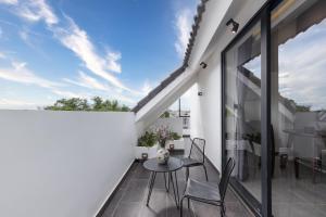 uma varanda com uma mesa e cadeiras numa parede branca em Anchie Retreat Villa Hội An em An Bàn (2) mais 6 fotografias