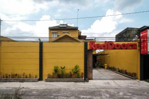 a yellow building with a red sign on it at RedDoorz at Solo Baru in Grogol