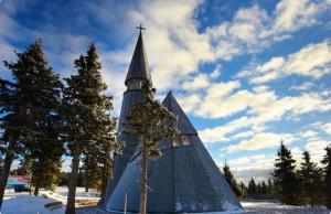 a church steeple with a cross on it in the snow at Apartma Ajdovka Rogla in Rakovec