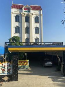 Khách Sạn Khánh Bình - Bình Dương في Tân Uyên: مبنى أبيض كبير مع سيارة متوقفة أمامه