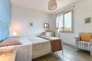 een slaapkamer met een bed, een stoel en een raam bij Appartamento Lucia in Capoliveri