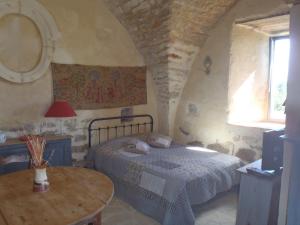 a bedroom with a bed and a table and a window at Chapelle du Domaine de Bombes in Saint-Rome-de-Dolan