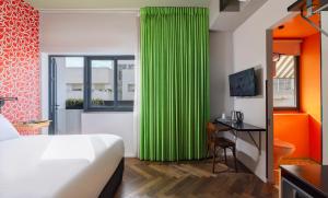 a bedroom with a bed and a desk with a monitor at Scarlet Hotel in Tel Aviv