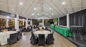 Un salón de banquetes con mesas blancas y sillas negras. en Orator Hotel, en Siusega