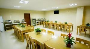 GreenTree Inn Shanghai Sheshan national tourist resort Express Hotel في Fenghuangshan: غرفة طعام مع طاولات وكراسي خشبية