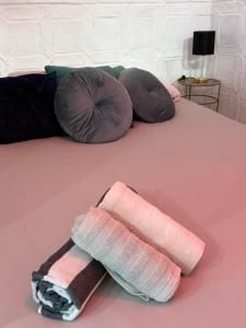 a pink bed with pillows and a towel on it at Gollum-Goretti House in Mairena del Aljarafe
