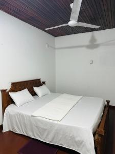 1 dormitorio con cama blanca y techo en Pawana Hotel, en Unawatuna