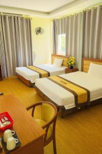 a hotel room with three beds and a table at Hương Sen Hotel Bac Giang in Bắc Giang