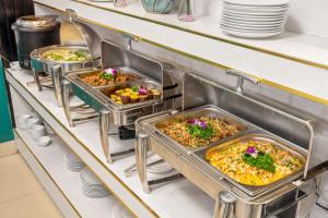 a buffet line with three trays of food at ELC Luxury Hotel Danang - An Thuong Walking Street in Da Nang