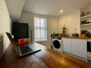 um computador portátil sentado numa mesa de madeira numa cozinha em Cosy Cottage Apperley Bridge em Apperley Bridge