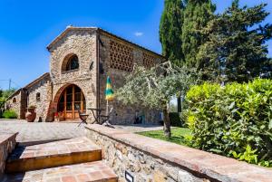 a stone building with a table and a umbrella at Monti 1824 - Apartments & Cottages in Casole dʼElsa