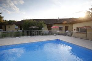a swimming pool in front of a house at Hôtel La Rocade in Pamiers