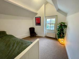 um quarto com uma cama, uma planta e uma janela em Cosy Cottage Apperley Bridge em Apperley Bridge mais 3 fotografias