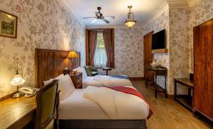 Habitación de hotel con 4 camas y escritorio. en Rokeby Manor, en Invergarry