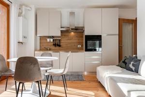 Siera View Apartment - Comfort e Relax a Sappada في سابادا: مطبخ مع خزائن بيضاء وطاولة وكراسي