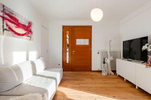 Siera View Apartment - Comfort e Relax a Sappada في سابادا: غرفة معيشة بيضاء مع أريكة بيضاء وتلفزيون