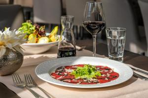 a plate of pizza on a table with a glass of wine at Best Western Victor's Residenz-Hotel Rodenhof in Saarbrücken
