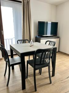 a dining room table with chairs and a television at Bormio365 Chalet in Valdisotto