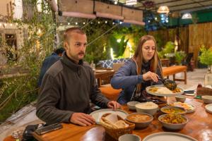 a man and woman sitting at a table eating food at TLO - The Life Outdoor, Bir Billing in Bīr