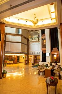 un gran vestíbulo con mesas y sillas en un edificio en The Chancery Hotel, en Bangalore