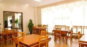 a dining room with wooden tables and chairs at GreenTree Inn Zhongshan Nanlang Metro Station Branch in Xiazha