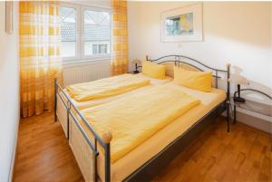 una camera da letto con un letto con lenzuola gialle e una finestra di Haus Sanderling Meeresbrise a Loog