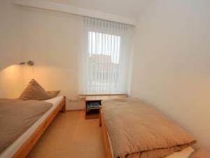 a small bedroom with two beds and a window at Haus Nixe Stranddüne in Juist