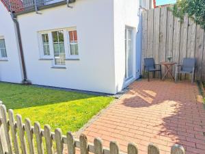 a white house with a fence and a patio at ENA Ferien Strandhütte in Juist +3 photos