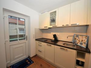 a kitchen with white cabinets and a sink and a window at ENA Ferien Strandkiste in Juist
