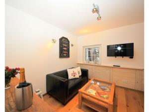 a living room with a black leather chair and a flat screen tv at ENA Ferien Strandkiste in Juist