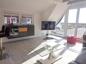 a living room with a glass table and a television at ENA Ferien Strandloft in Juist