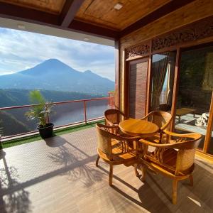 a table and chairs on a balcony with a view of a mountain at Bagas Luxury Camp in Kejajar