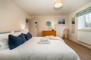 a bedroom with a large white bed with blue pillows at Garsington Studios Chilterns Farm House - Pass the Keys in Stokenchurch