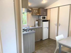 a small kitchen with a stove and a refrigerator at ZEcamping 3 étoiles chiens acceptés piscine et bar restaurant in Sartène