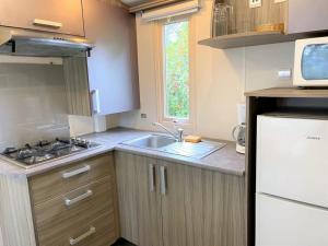 a small kitchen with a sink and a refrigerator at ZEcamping 3 étoiles chiens acceptés piscine et bar restaurant in Sartène