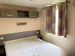 a bedroom with a bed and a window with curtains at ZEcamping 3 étoiles chiens acceptés piscine et bar restaurant in Sartène