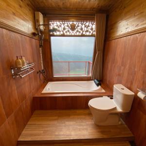 a bathroom with a tub and a toilet and a window at Bagas Luxury Camp in Kejajar +48 photos