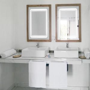 un baño con dos lavabos y dos espejos en Duna Serena Tiny Houses, en Praia do Tofo