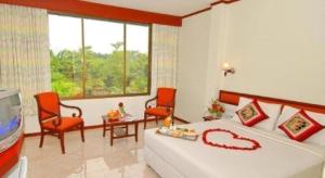 a bedroom with a bed and two chairs and a tv at Phatad Valley Hotel in Ban Kui Mang