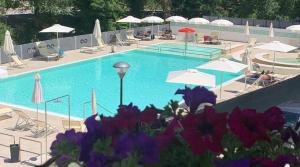 a swimming pool with umbrellas and tables and chairs at Hotel Terme di Frasassi in Genga
