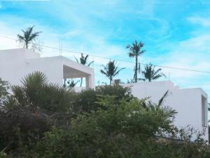 a white house with palm trees in the background at Duna Serena Tiny Houses in Praia do Tofo