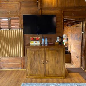 ein Unterhaltungszentrum mit einem TV an einer Holzwand in der Unterkunft Bagas Luxury Glamping in Kejajar