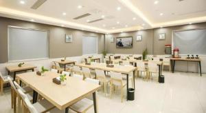 GYA Jiaxing Tongxiang City Century Avenue Hotel في Tongxiang: فصل دراسي يحتوي على طاولات وكراسي في الغرفة