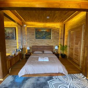 ein Schlafzimmer mit einem großen Bett und einer Holzwand in der Unterkunft Bagas Luxury Glamping in Kejajar