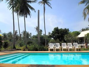 a group of chairs and a swimming pool with palm trees at Jinta Beach Bungalow in Ban Phang Ka